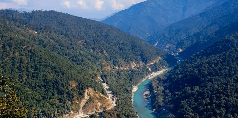 Breathtaking view of the river winding through lush green mountains under a clear blue sky in Darjeeling.