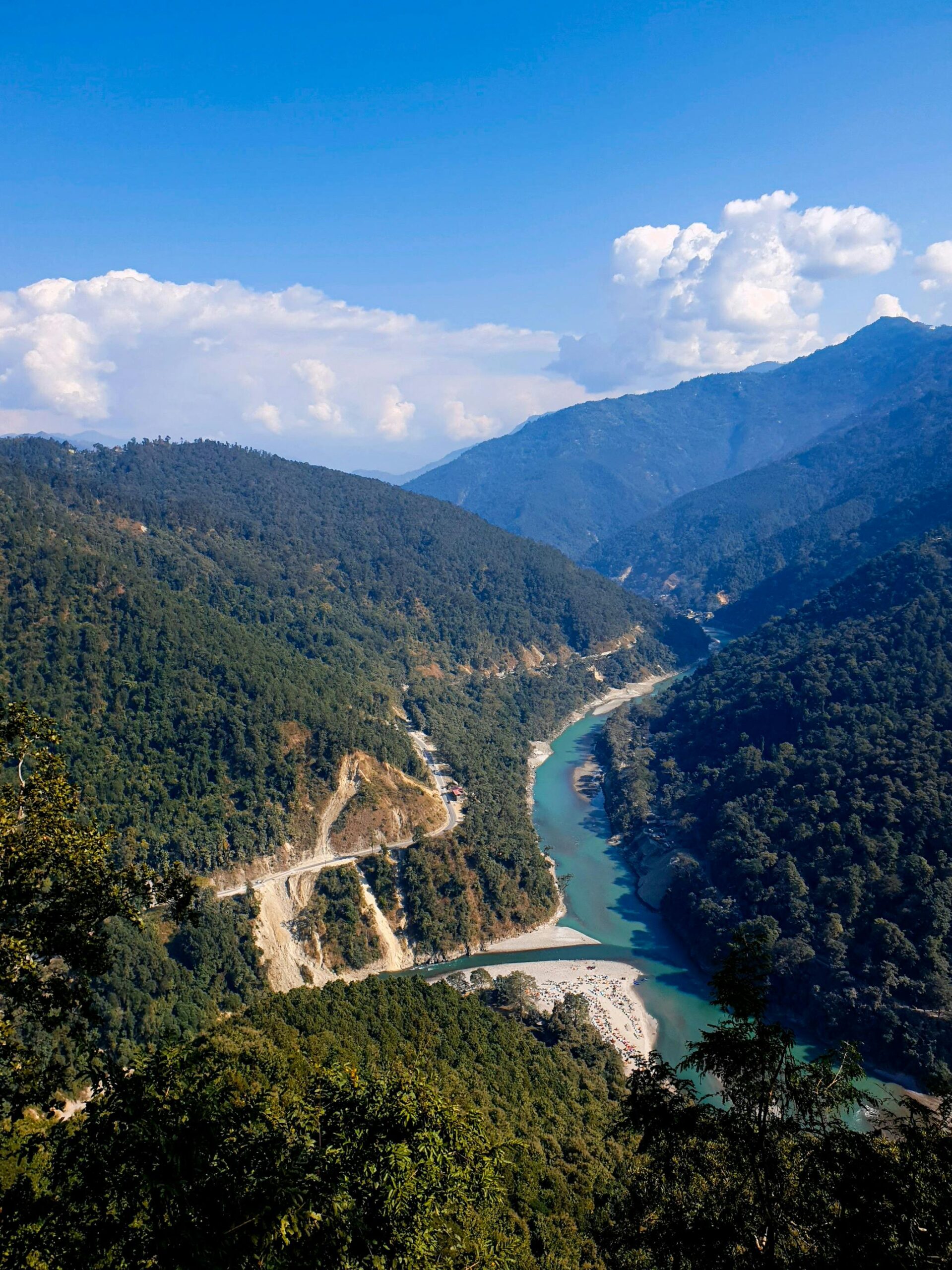 Breathtaking view of the river winding through lush green mountains under a clear blue sky in Darjeeling.