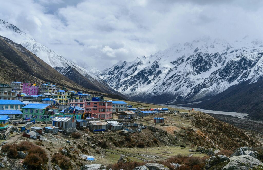 Colorful alpine village in Sikkim, India with snowy mountains backdrop.