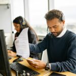 Call center agents with headsets working in a modern office setting, reviewing documents.